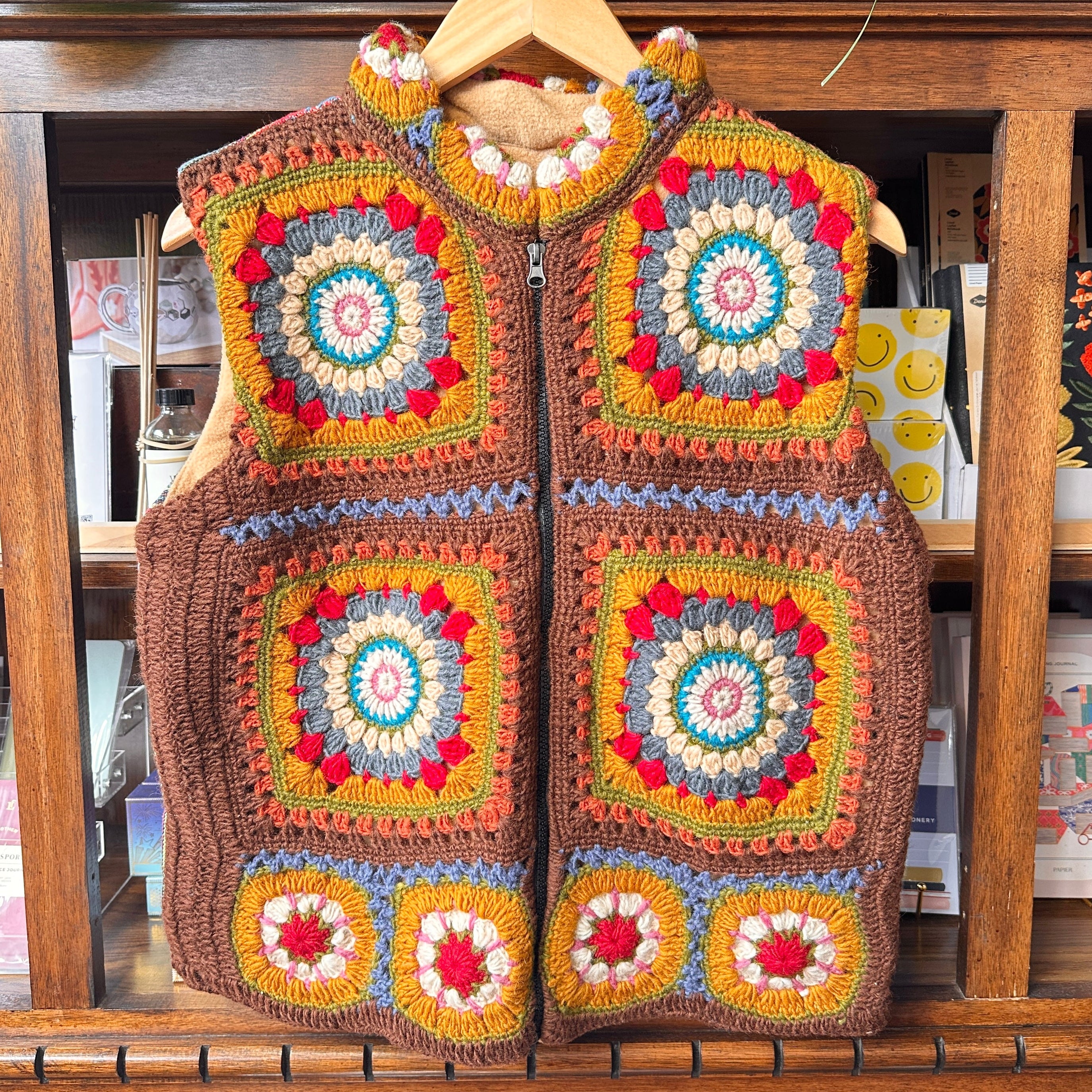 A handmade crocheted zip-front vest with colorful granny square panels.