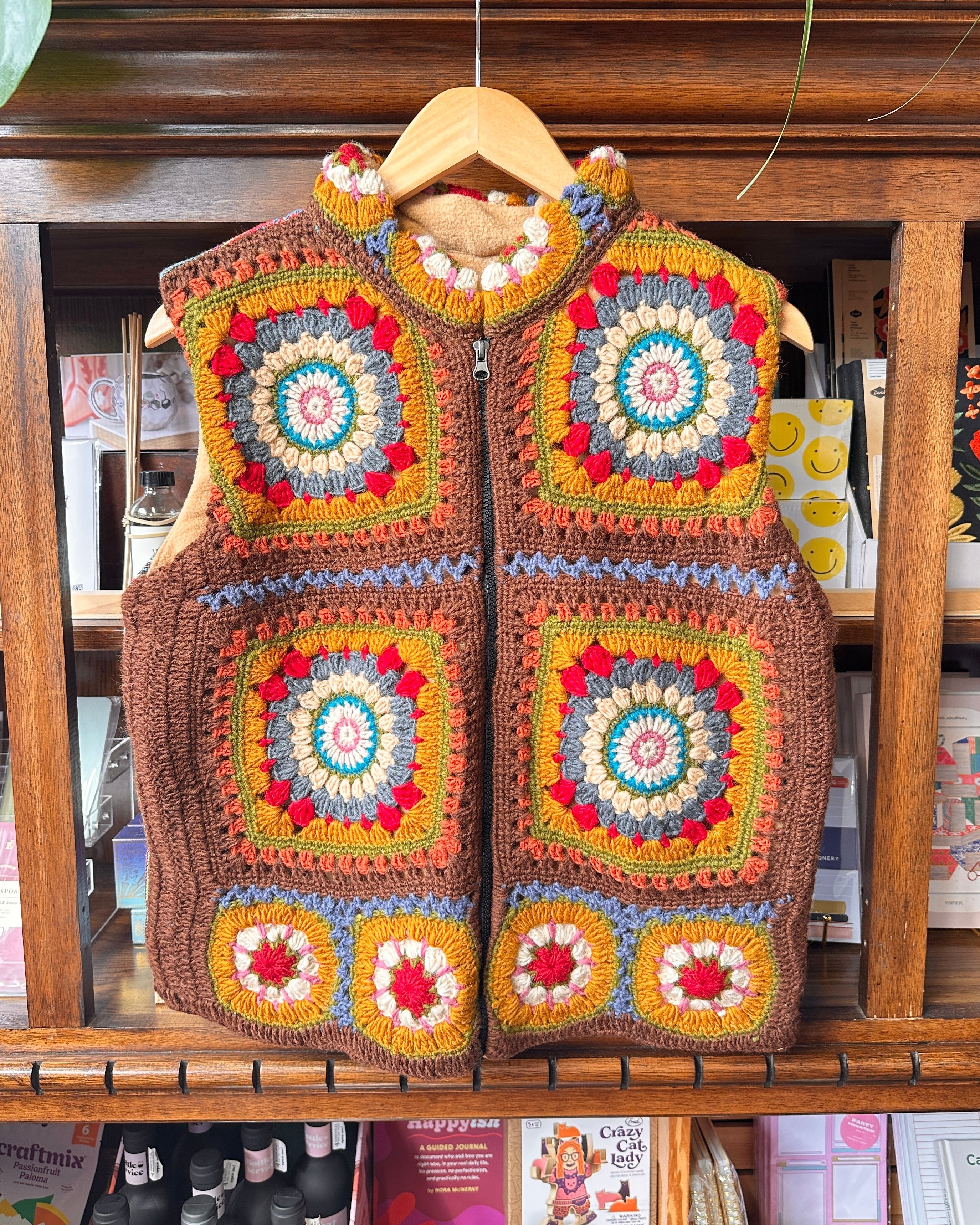 A handmade crocheted zip-front vest with colorful granny square panels.