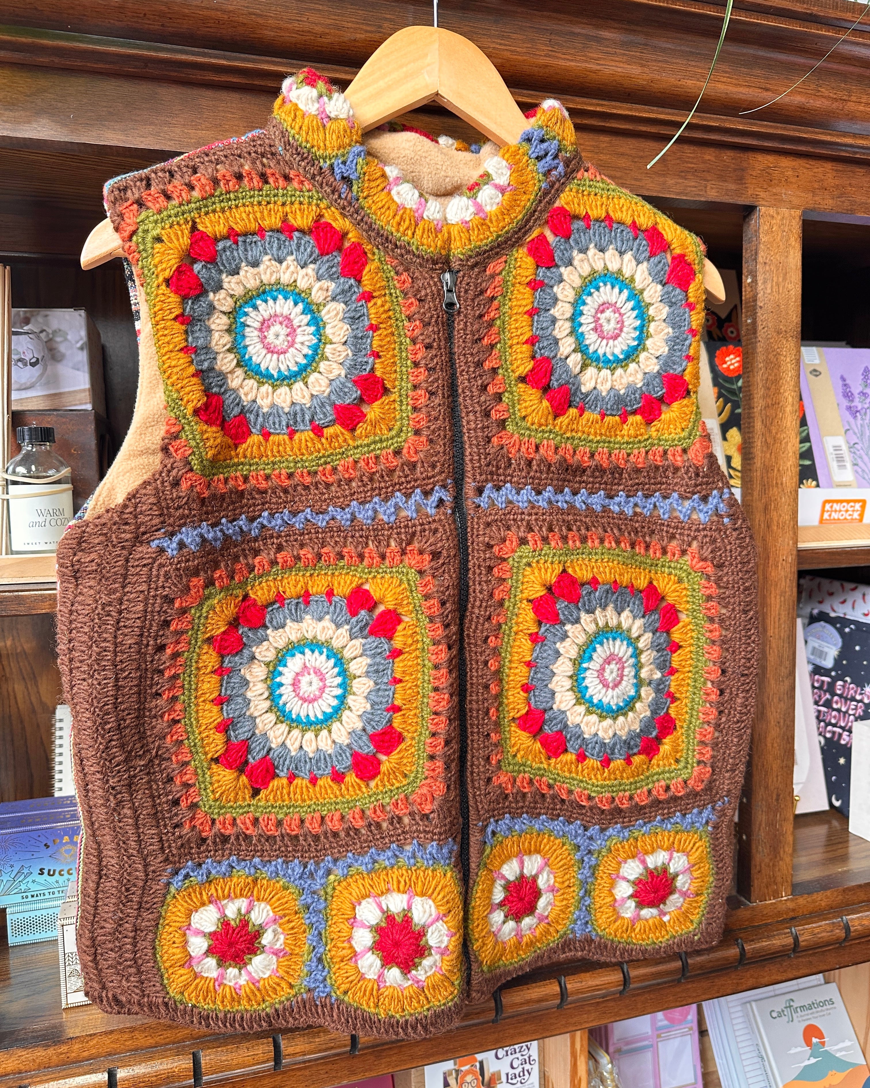A handmade crochet vest with a colorful granny square pattern.