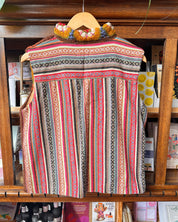 A sleeveless bohemian-style woven vest with vertical stripes and geometric patterns in pink, red, green, black, and beige.