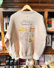 A light beige crewneck sweatshirt with a 'Fall Bucket List' embroidered print.