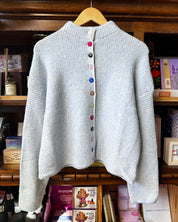 A light blue and white striped textured knit cardigan sweater with a high mock neck and colorful decorative buttons.