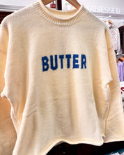 Yellow-colored fuzzy knit sweater with 'BUTTER' written across the chest in blue letters.