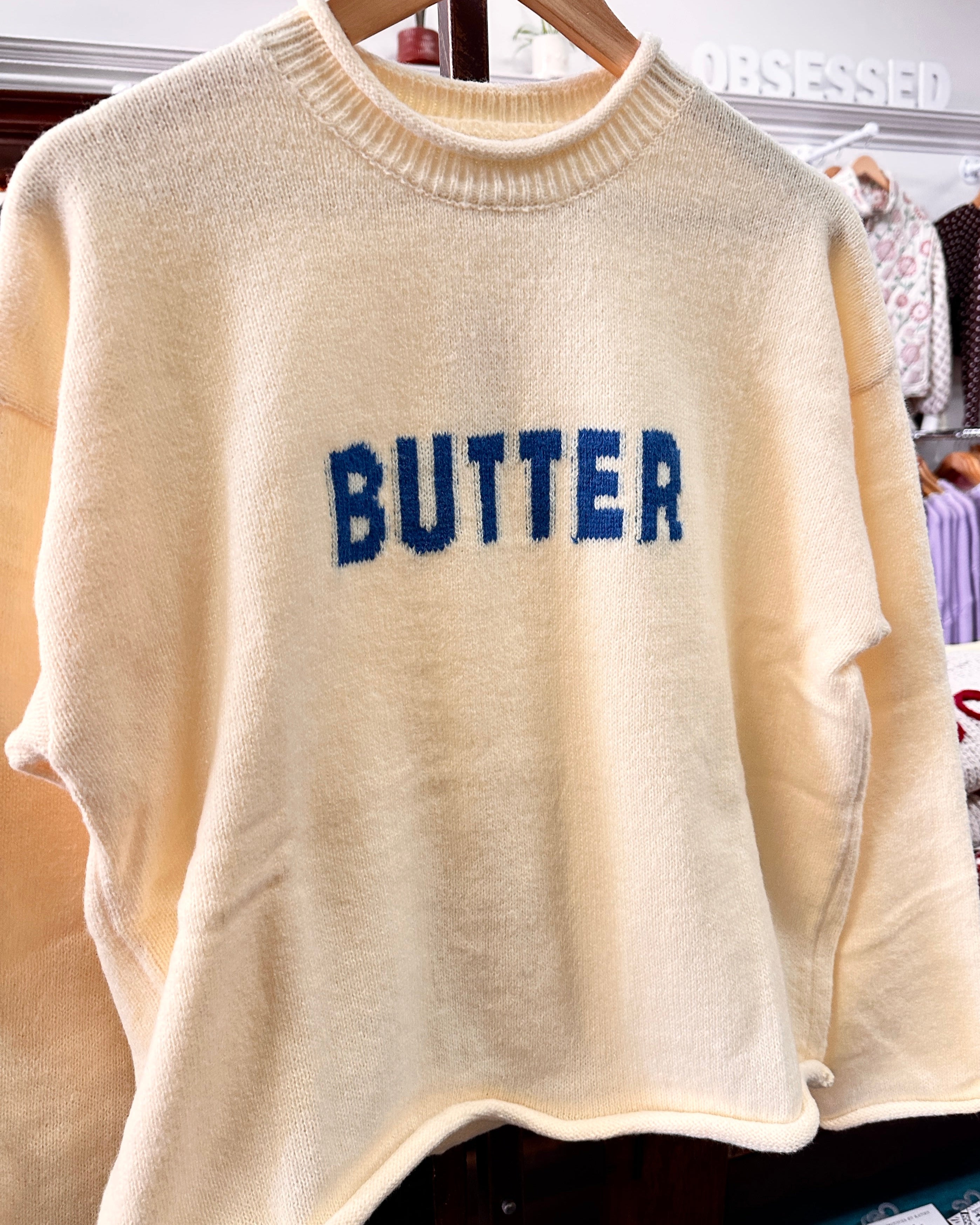 Yellow-colored fuzzy knit sweater with 'BUTTER' written across the chest in blue letters.