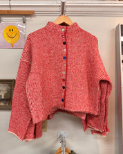 A red and white striped knit cardigan with a high mock neck and colorful decorative buttons down the front.