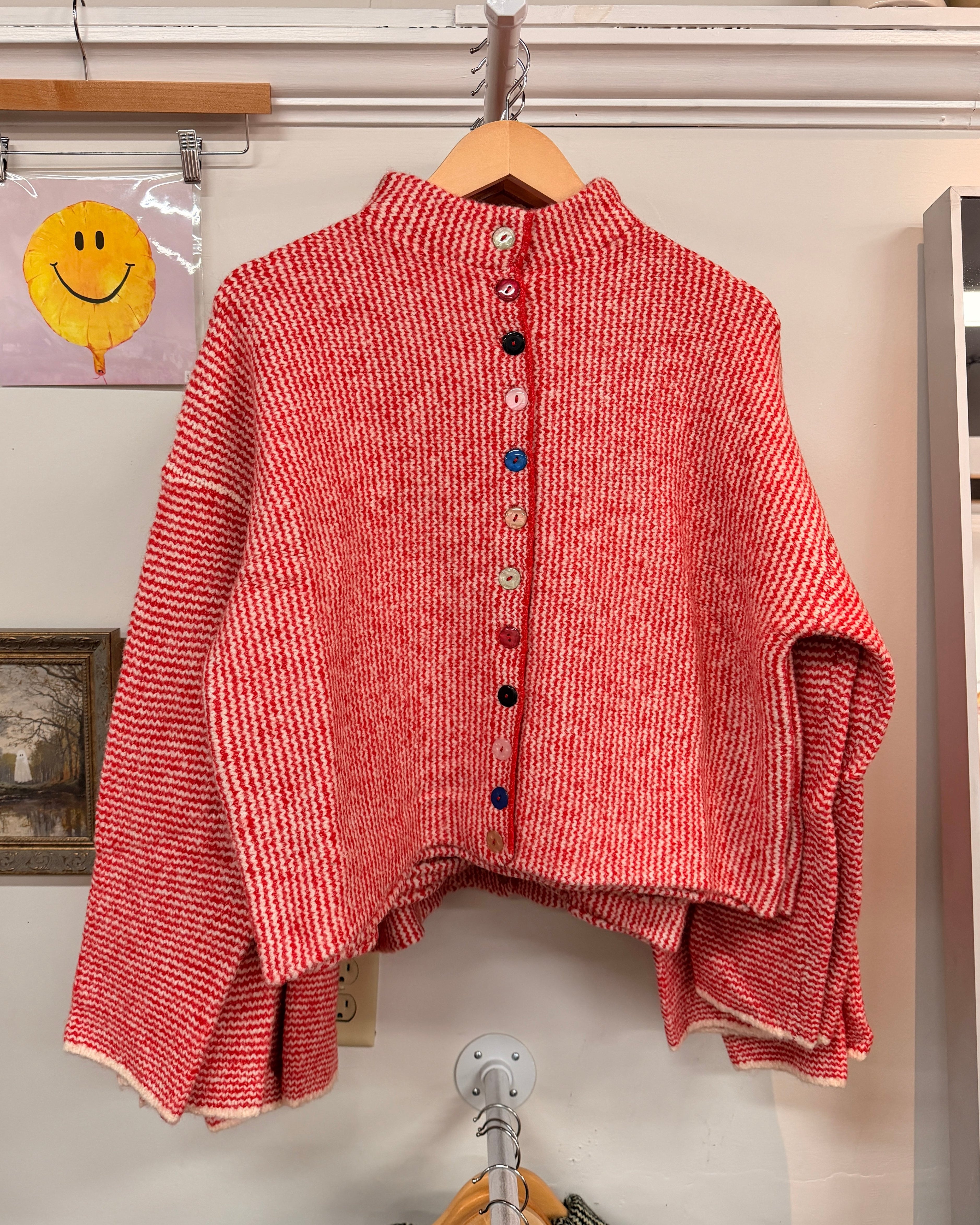 A red and white striped knit cardigan with a high mock neck and colorful decorative buttons down the front.
