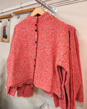 A red and white striped knit cardigan with a high mock neck and colorful decorative buttons down the front.